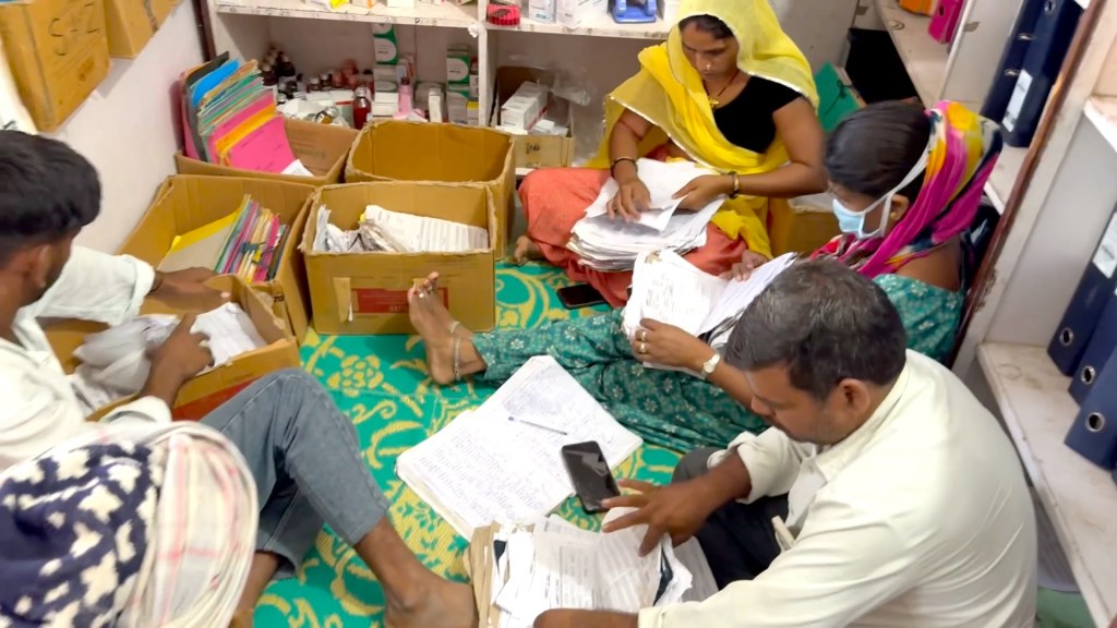 Two men and two women seated on the floor, looking through stacks of paper